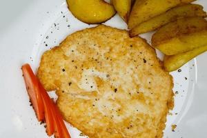 Chicken schnitzel, served with tomato and potatoes. Top view. photo