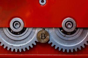 engranajes y cogs de cerca y moneda bitcoin foto