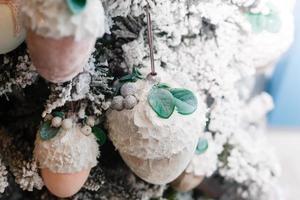 white New Year tree decorated with toys and balls, and flashing candles garland. Christmas background with grunge plaster wall photo