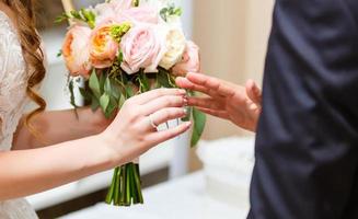 The bride's hand wears an engagement ring on the groom's finger. Hands with wedding rings. Close up. photo