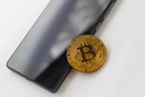 criptomoneda bitcoin de oro con un teléfono inteligente foto