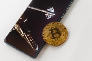 criptomoneda bitcoin de oro con un teléfono inteligente en una mesa de madera foto