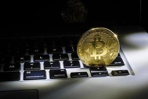 moneda nueva de bitcoin dorado, aceptando bitcoin para pago, concepto de finanzas, espacio de copia de computadora portátil foto