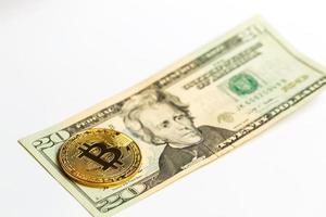 Gold bitcoin on a white background next to us paper money with a face value of dollars photo