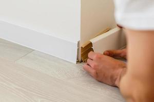 Mans hands putting white baseboard photo