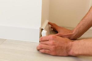 Mans hands putting white baseboard photo