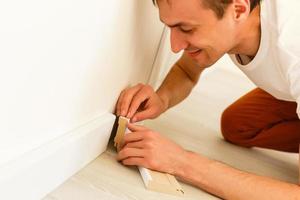 Man putting new skirting board in house photo