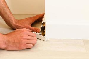 Worker in unifor installing baseboard at the bottom of the wall photo