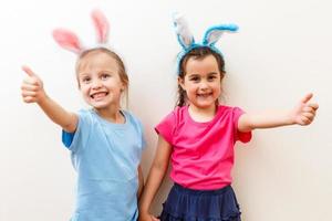 Two smiling girls with rabbit ears holding a box with easter eggs on background. photo