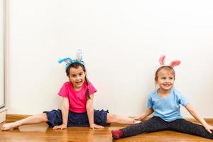 Two smiling girls with rabbit ears holding a box with easter eggs on background. photo