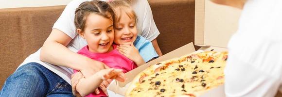 Happy family eating pizza on the wooden table photo