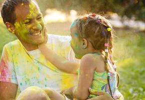 Father mother and daughter playing in the park and showering with paints photo