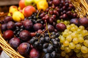 Apples plums and grape on a wooden background freshly washed on a plate photo