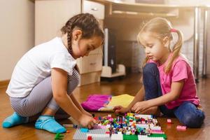 dos lindos niños pequeños están jugando con bloques niñas felices en casa graciosas hermanas encantadoras foto