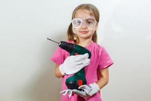 Little smiling girl holding a drill photo