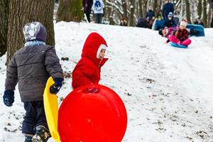 Little girl sledging down hill bright and joyful winter scene photo