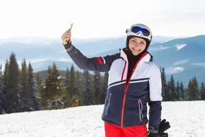 winter, leisure, sport and people concept, happy young woman in ski clothes outdoors photo