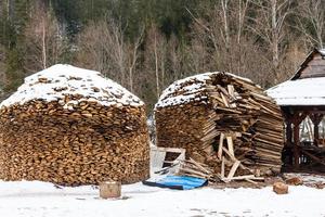 leña apilada en invierno. pila de madera con nieve apilada para leña. stock picado de leña bajo la nieve. montones de leña cubierta de nieve en el frío día de invierno foto
