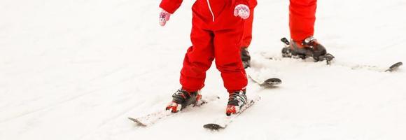 linda niña aprendiendo a montar en los esquís niño dando sus primeros pasos diversión al aire libre para la familia foto