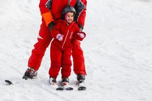 Professional ski instructor is teaching a child to ski on a sunny day on a mountain slope resort with sun and snow. Family and children active vacation. photo