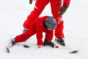 Professional ski instructor is teaching a child to ski on a sunny day on a mountain slope resort with sun and snow. Family and children active vacation. photo