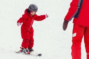Girl child is learning to ski get up after a fall she slowly slides on skis in soft fresh snow photo