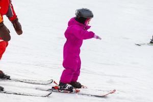 little girl learns to ski with the help of an adult photo