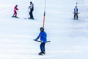 children on a ski lift, ski-lift and snow-capped mountains. photo