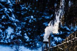 Smoking pipe on a snowy roof in a cold winter day photo