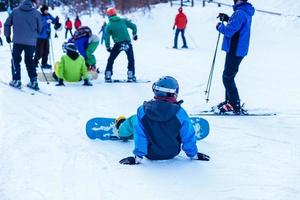 Snowboarder sitting. Winter sport concept with adventure guy on top of mountain ready to ride down photo