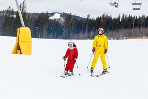una niña y una mujer están esquiando montaña abajo foto