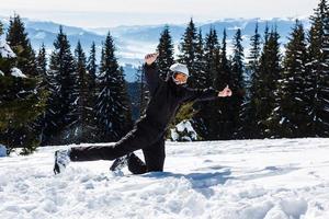 A skier or snowboarder stands on a hill or a slope on a background of mountains covered with forests and snow-covered. They fool around and laughing, happy and rejoice photo