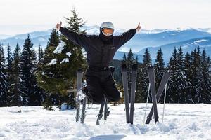 A skier or snowboarder stands on a hill or a slope on a background of mountains covered with forests and snow-covered. They fool around and laughing, happy and rejoice photo