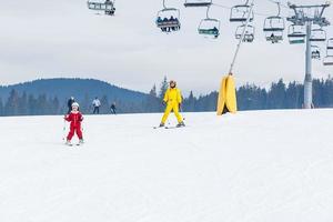 Little girl and a woman are skiing down a mountain photo