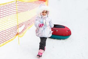 Little girl with snowtube is going to sledding photo