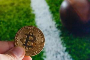 Golden bitcoin coin against digital currency sport, ball background photo