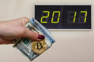 Golden bitcoin coin on women's hand on blurred us dollar bills background copy space 2017,  year, dog photo