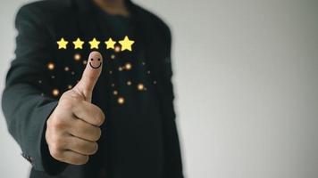 Customer satisfaction concept. Hand with thumb up Positive emotion smiley face icon and five star with copy space. photo