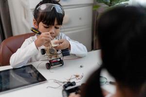 Asia students learn at home in coding robot cars and electronic board cables in STEM, STEAM, mathematics engineering science technology computer code in robotics for kids concept. photo