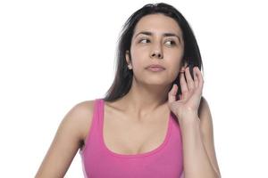 What, say louder, cannot hear you. Confused intense and annoyed woman in pink t-shirt, gesturing palm cluelessly, holding hand near ear photo