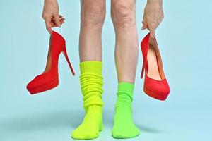 woman with two different sports socks wearing elegant red high hills isolated on blue background photo