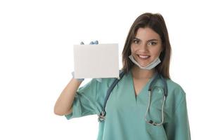 Young smiling woman nurse or doctor in scrubs showing empty blank sign board with copy space photo