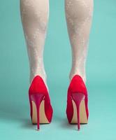 back view of woman's feet wearing red high hills. isolated on blue background photo