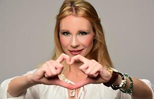 retrato de una hermosa mujer feliz sosteniendo las manos en forma de corazón foto