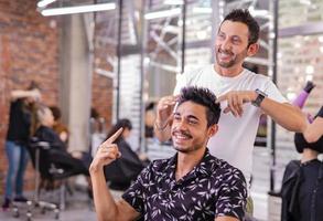 Handsome Arab man is getting shaved by hairdresser at the barbershop photo