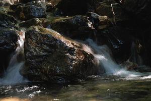 primer plano de rápidos de agua borrosos que fluyen sobre una piedra foto