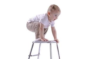 niño sube a una silla de escalera. el comienzo de un concepto de carrera. niño divertido aislado sobre fondo blanco.