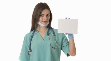 Young smiling woman nurse or doctor in scrubs showing empty blank sign board with copy space photo