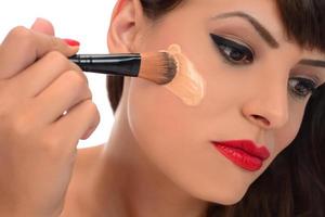 maquillaje diario. mujer joven sonriente aplicando rubor con pincel de maquillaje foto