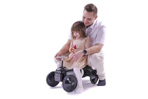 niña y su padre montando un coche de juguete de estilo retro. foto